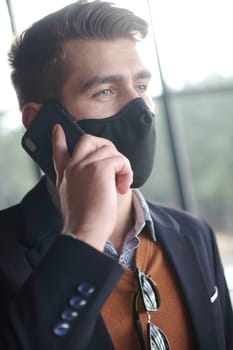 business man wearing coronavirus  protective  medical face mask while using smartphone and new normal smart  technology