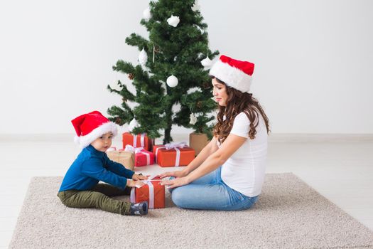 Christmas, single parent and holidays concept - Cute little boy holding christmas present for his mother at the home