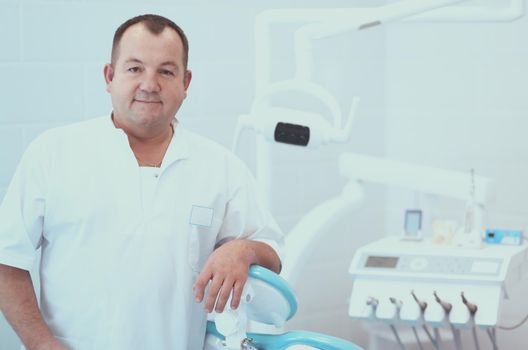 Portrait of a smiling dentist standing in dental clinic.
