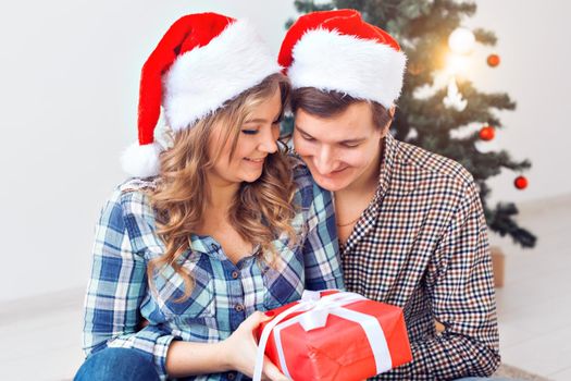 Family, x-mas, winter holidays and people concept - happy couple hugging near christmas tree at home.