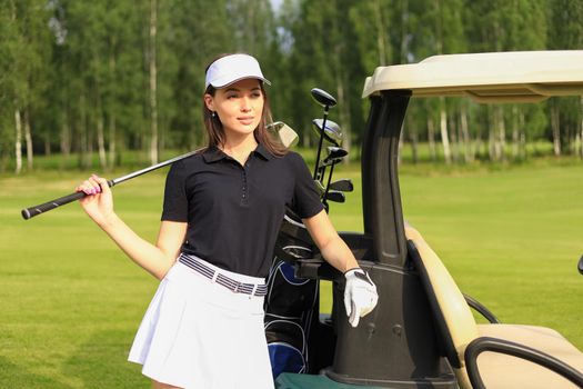 Beautiful cheerful woman standing near in golf cart