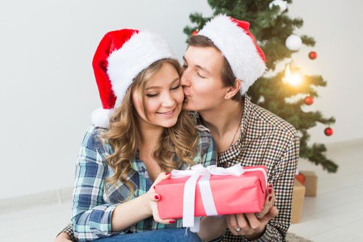 Family, x-mas, winter holidays and people concept - happy couple hugging near christmas tree at home.