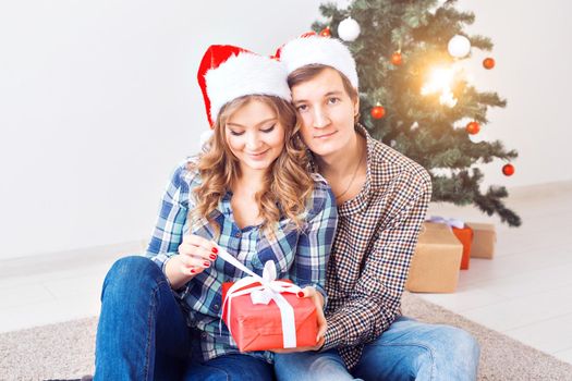 Family, x-mas, winter holidays and people concept - happy couple hugging near christmas tree at home.