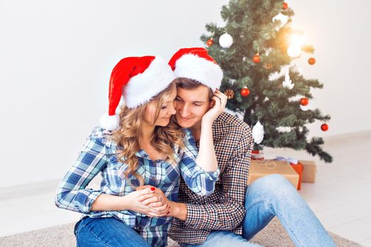 Family, x-mas, winter holidays and people concept - happy couple hugging near christmas tree at home.