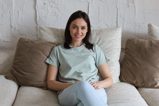 Beautiful young woman sitting on sofa, indoors