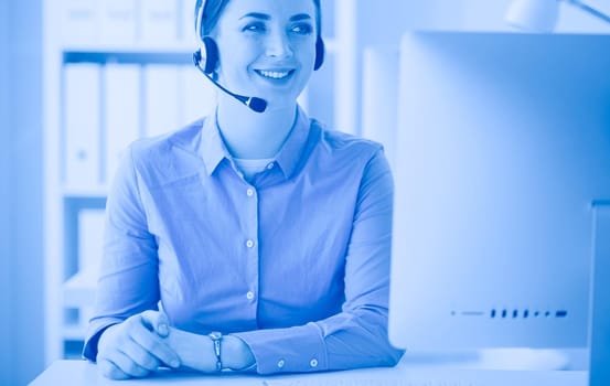 Serious pretty young woman working as support phone operator with headset in office.