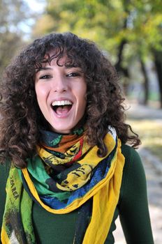 brunette Cute young woman with colorful scarf smiling outdoors in nature
