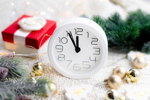 A clock on the beach with a garland . A white watch. Cozy vibes . Home comfort. New Year and Christmas. Decorating