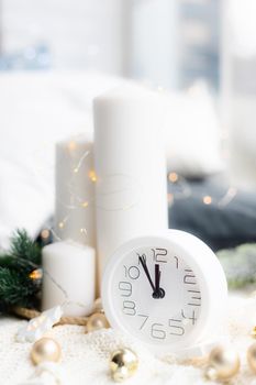 A clock on the beach with a garland . A white watch. Cozy vibes . Home comfort. New Year and Christmas. Decorating