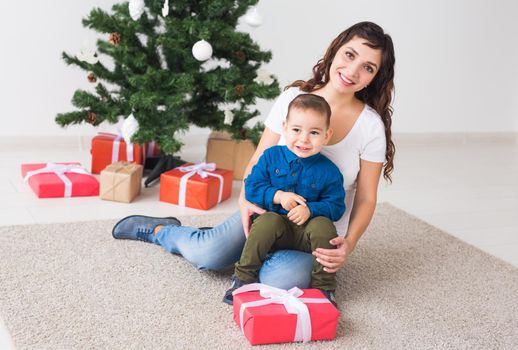 Christmas, single parent and holidays concept - Cute little boy holding christmas present for his mother at the home