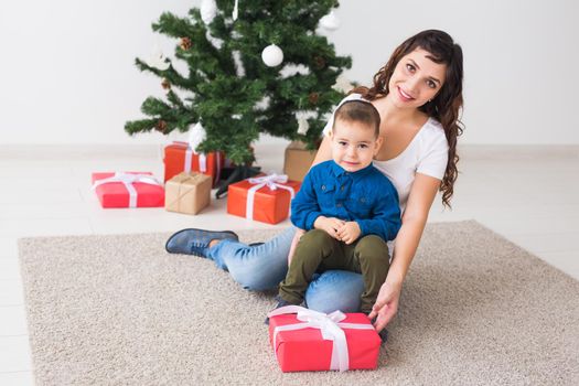 Christmas, single parent and holidays concept - Cute little boy holding christmas present for his mother at the home