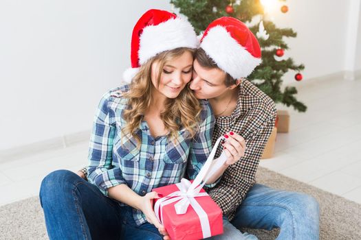 Family, x-mas, winter holidays and people concept - happy couple hugging near christmas tree at home.