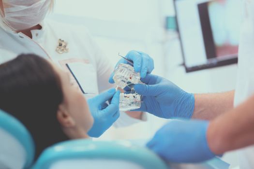 Senior male dentist in dental office talking with female patient and preparing for treatment.