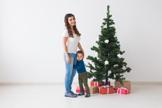 Christmas, single parent and holidays concept - Cute little boy and his mother standing near christmas tree.