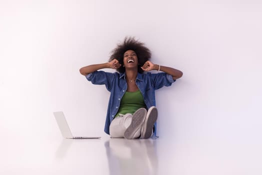 Portrait of happy young african american woman sitting on floor with laptop