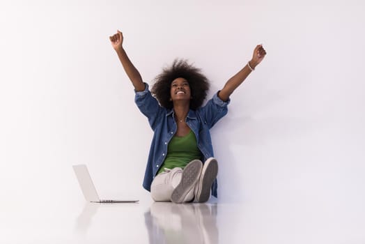 Portrait of happy young african american woman sitting on floor with laptop