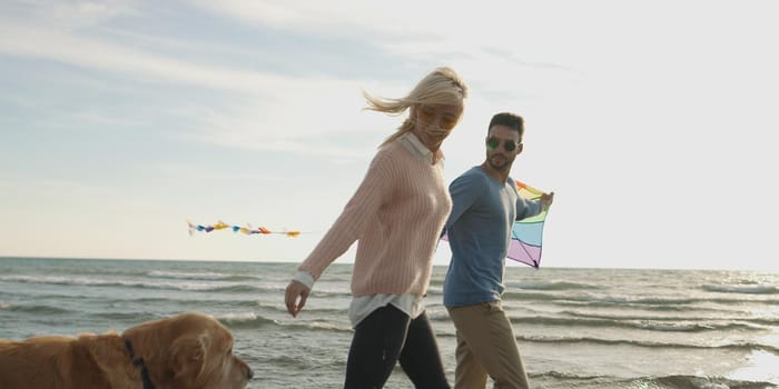 Couple Running On The Beach Holding Their Hands with dog On autmun day