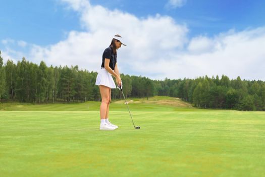 Beautiful woman golfer prepare to shot on ball on the green golf course