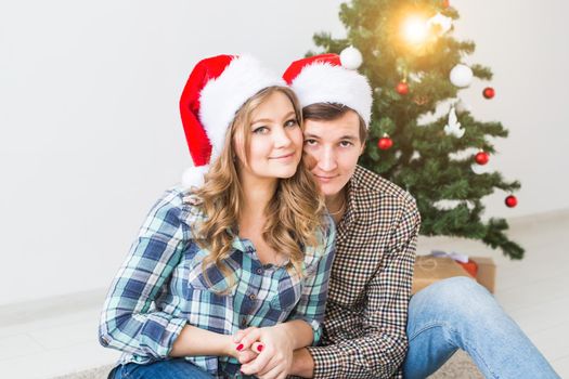 Family, x-mas, winter holidays and people concept - happy couple hugging near christmas tree at home.