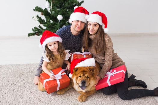 Pet, holidays and festive concept - Family with dog are lying on floor near christmas tree