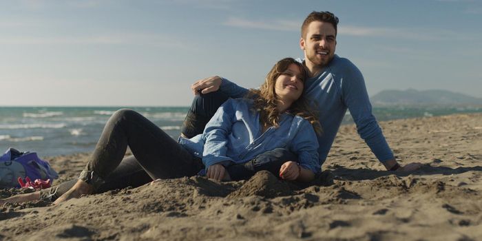 Young Couple having fun and Playing With A Kite On The Beach at autumn day