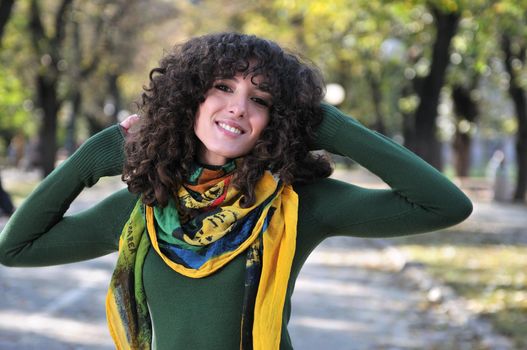 brunette Cute young woman with colorful scarf smiling outdoors in nature
