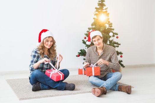 Holidays, christmas and family concept - Young happy couple opening gifts at home