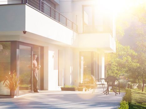 portrait of a young successful man drinking coffee in the doorway of his luxury home villa