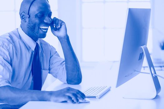 African american businessman on headset working on his laptop.