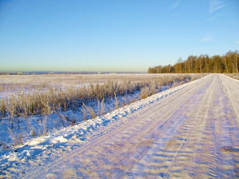 The snow-covered road is an early, sunny, frosty morning in the suburbs.