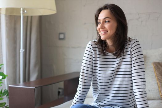 Beautiful young woman sitting on sofa, indoors