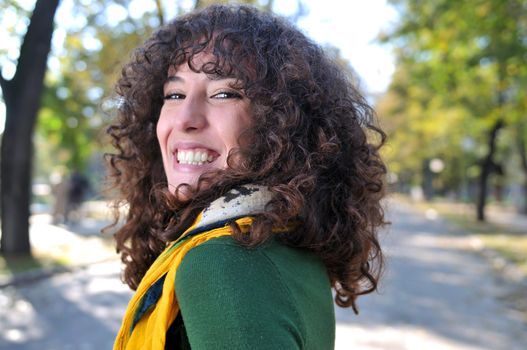 brunette Cute young woman with colorful scarf smiling outdoors in nature
