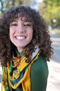 Young curly woman smiling outdoors in nature