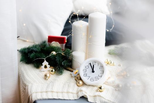 A clock on the beach with a garland . A white watch. Cozy vibes . Home comfort. New Year and Christmas. Decorating