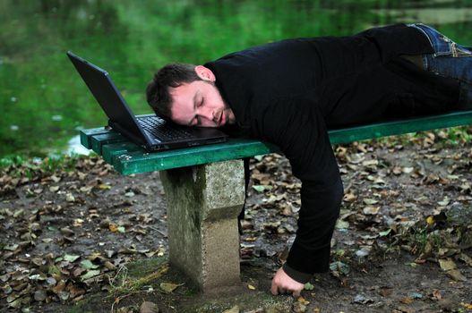 young businessman sleeping with head on laptop