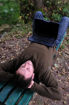 one young businessman working on laptop outdoor with green nature in background