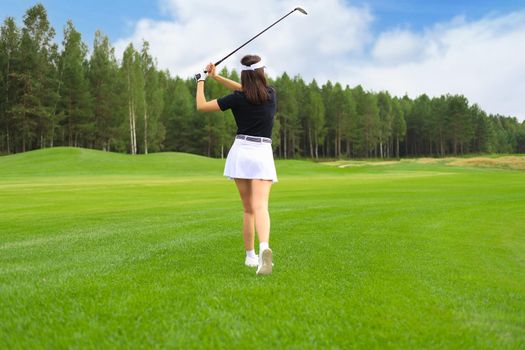 Woman golfer hits an fairway shot towards the club house