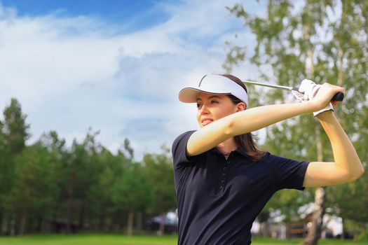 Woman golfer hits an fairway shot towards the club house
