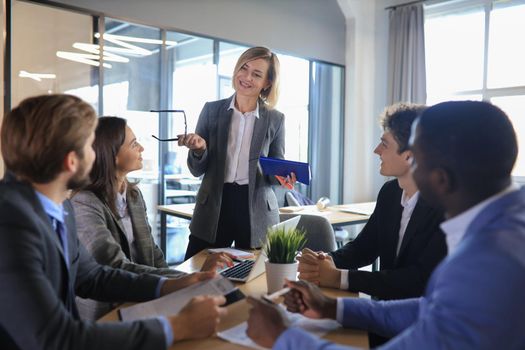 Female boss addressing meeting around boardroom table