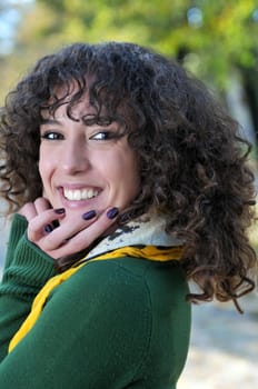 Young curly woman smiling outdoors in nature