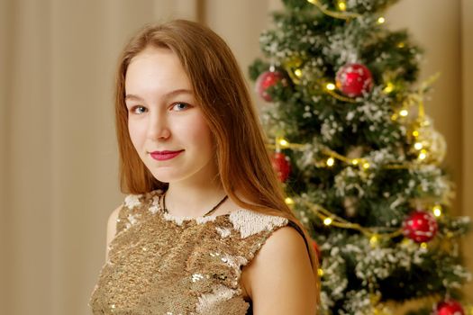 A teenage girl near the New Year tree. Concept Christmas, family holidays.