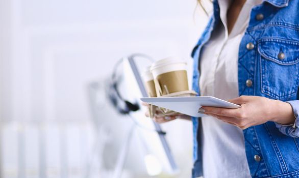 Smiling woman drinking coffee and using tablet in the cafe