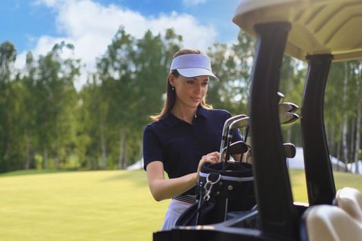 Professional woman golf player choosing the golf club from the bag