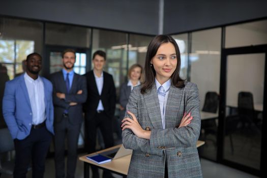 Business woman with her staff, people group in background at modern bright office indoors