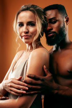 Young pretty couple diverse races together posing sensitive on brown background, lifestyle people concept close up