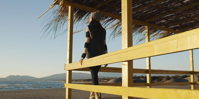 Young woman on the beach. The girl enjoying the warm autumn day. Portrait of beautiful girl near the water