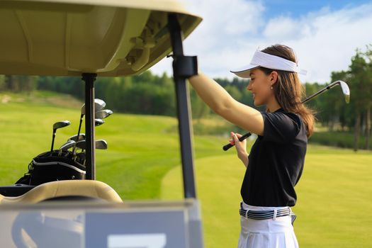 Professional woman golf player choosing the golf club from the bag
