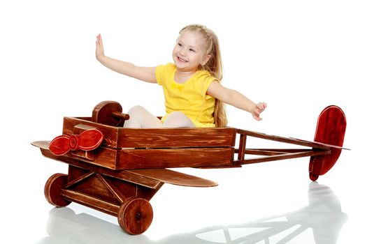 A lovely little round-faced blonde girl, with very long beautiful hair, in short skirts and yellow jerseys.She is riding a toy plane.Isolated on white background.