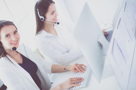 Smiling businesswoman or helpline operator with headset and computer at office.