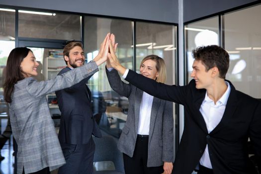 Happy people standing in office and giving high five to their colleagues
